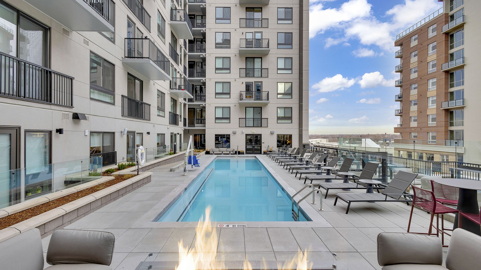 pool with outdoor seating, lounge chairs, fire pit with a view of Denver