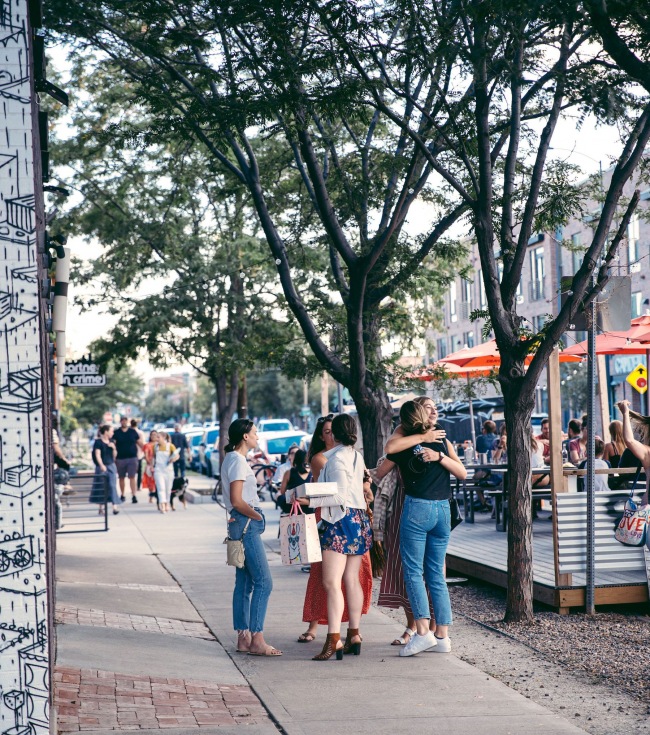 people hugging on a spacious local street of storefronts